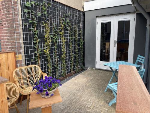 a patio with a table and chairs and purple flowers at Studio Pipper in Zandvoort