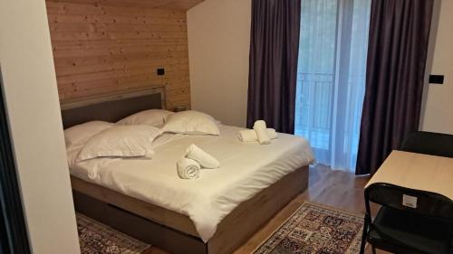 a bedroom with a bed with white sheets and pillows at Casa dintre Brazi in Statjunea Borsa