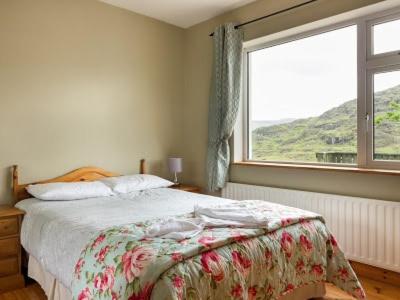 a bedroom with a bed and a large window at Black Valley lodge in Killarney