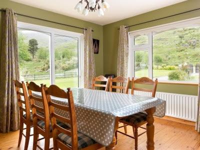 a dining room with a table and chairs and windows at Black Valley lodge in Killarney