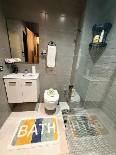 a bathroom with a toilet and a sink with a bath rug at Votre escapade d été à deux pas de la plage in Kenitra