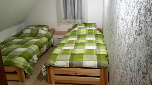 duas camas num quarto com lençóis verdes e brancos em Domek nad Jeziorem em Lepaki Wielkie