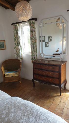 a bedroom with a dresser with a mirror and a chair at Quinta Martins in Loulé
