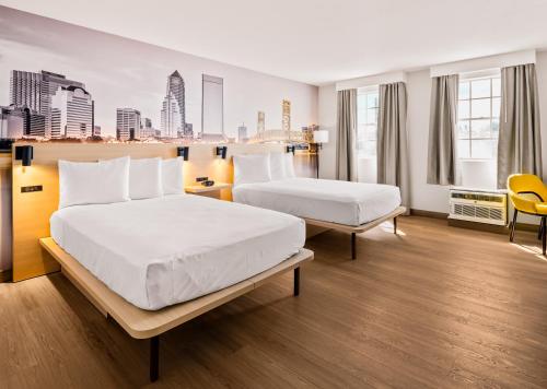 two beds in a hotel room with a city skyline at B&B HOTEL Jacksonville Airport - Newly Renovated! in Jacksonville