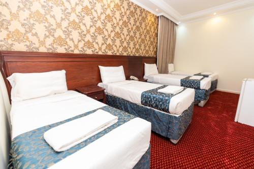 two beds in a hotel room with red carpet at فندق برج العالم 2 in Mecca