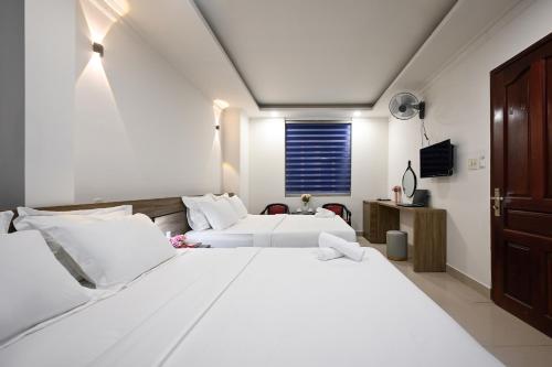 two white beds in a room with a window at Hotel Trung Mai-Sân Bay in Ho Chi Minh City