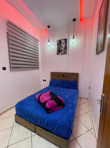a bedroom with a bed with blue sheets and pink walls at saviohome in Ouarzazate