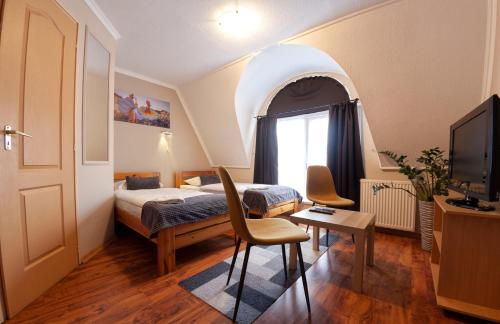 a bedroom with a bed and a table and a tv at Mátyás Szállás Panzió in Szombathely
