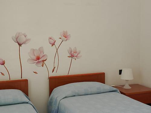 a bedroom with two beds with pink flowers on the wall at Albergo La Maria in Fiumaretta di Ameglia
