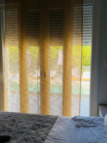 a bedroom with a bed and a window with curtains at Casa Nikolou Stegna in Archangelos