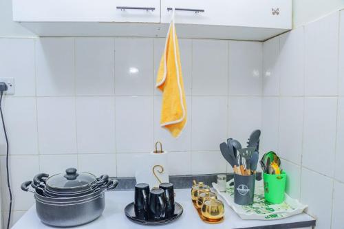 a kitchen counter with a stove with a pot and utensils at D&H Homes Milimani Nakuru-Elegant 2 Bedroom Apartment in Nakuru