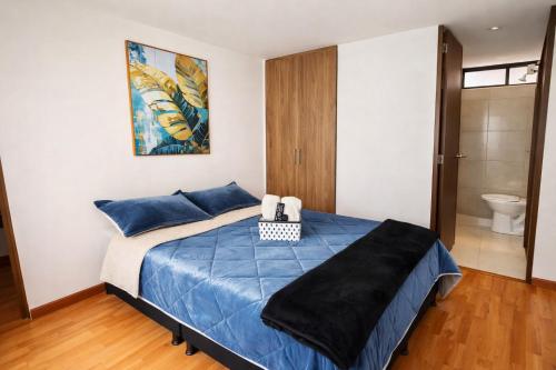 a bedroom with a bed with blue sheets and a bathroom at Apartaestudio con parqueadero cerca UPTC y Clínica Los Andes in Tunja