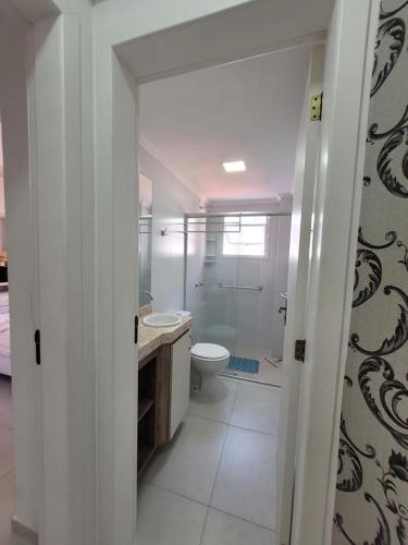 a bathroom with a toilet and a sink and a shower at Apartamento Completo Duas Quadras do Mar in Capão da Canoa