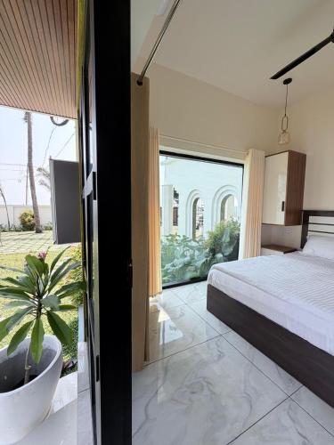 a bedroom with a bed and a large window at LAGUNA BLU beach villa in Irimbranallūr
