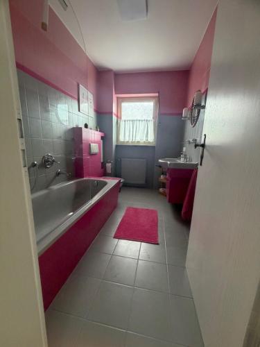 a pink bathroom with a tub and a sink at Ferienwohnung Kirschtraum in Mülheim-Kärlich