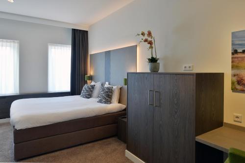 a bedroom with a bed and a wooden cabinet at Hotel de Leijhof Oisterwijk in Oisterwijk