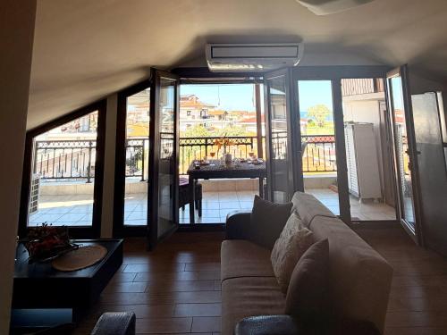 a living room with a couch and a balcony with a table at VASILICA Apartments in Ierissos