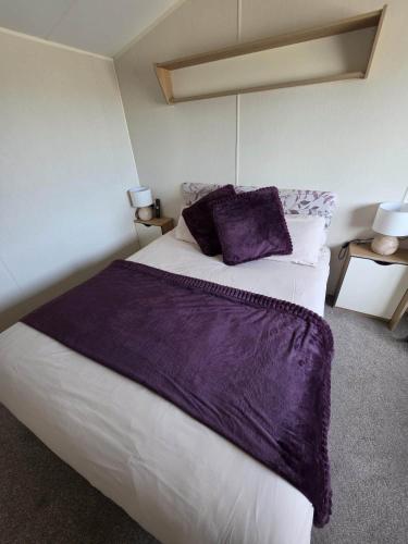 a bedroom with a large bed with a purple blanket at Devon Cliff Breaks in Exmouth