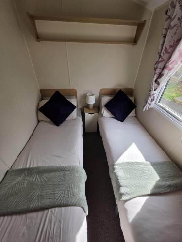 two twin beds in a small room with a window at Devon Cliff Breaks in Exmouth