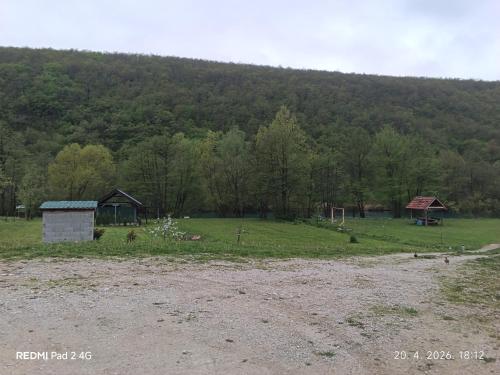 a field with a barn and a house in the distance at Kamp Suad in Zaglavica