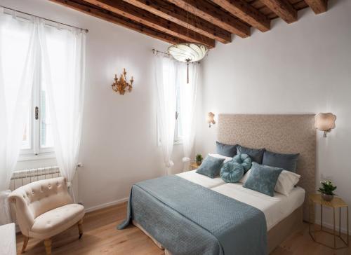 a bedroom with a large bed and a chair at Ca del Mar Venice Luxury Apartments in Venice