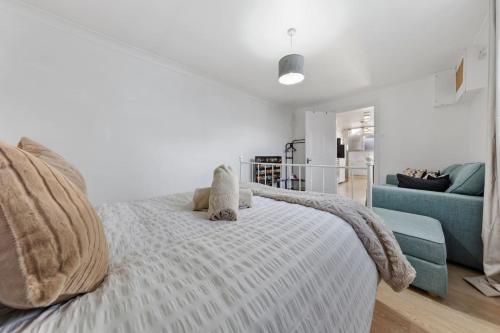a white bedroom with a bed and a blue couch at Private Annex with Gated Driveway near Grove Park Station in Hither Green