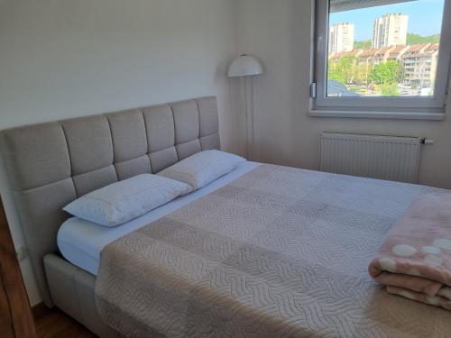 a bedroom with a bed with a large window at Apartman Milica in Doboj