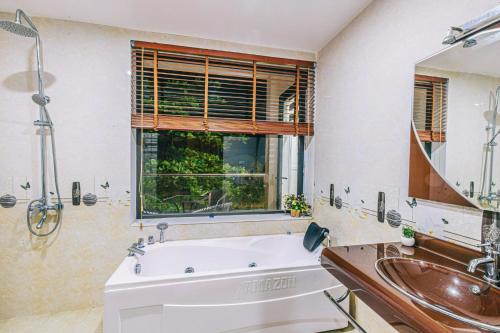 a bathroom with a tub and a sink and a mirror at FLC Grand Villa BT31-23 in Sầm Sơn