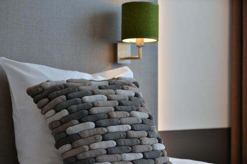 a pillow on a bed with a green lamp at Hotel de Leijhof Oisterwijk in Oisterwijk