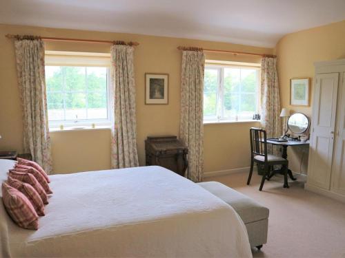 a bedroom with a bed and a desk and windows at 4 Bed in Bridport oc-dc195 in Loders