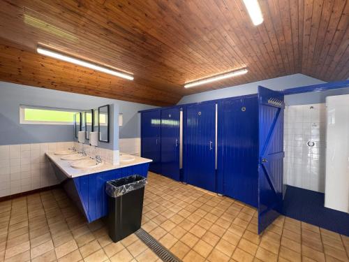 a blue bathroom with two sinks and a mirror at Little Green Glamping Pod in Narberth