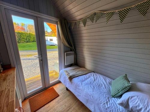 a small room with a bed in front of a window at Little Green Glamping Pod in Narberth