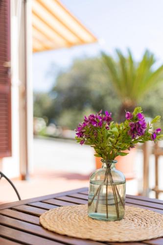 a vase with purple flowers sitting on a table at Appartamenti Bellavista by ElbaSummer in Portoferraio