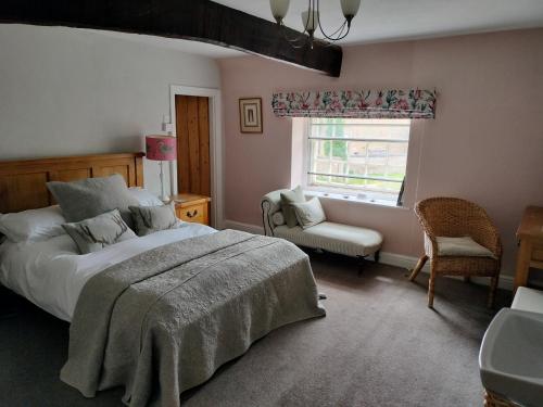 a bedroom with a bed and a chair and a window at Coxwold Tearoom in Coxwold