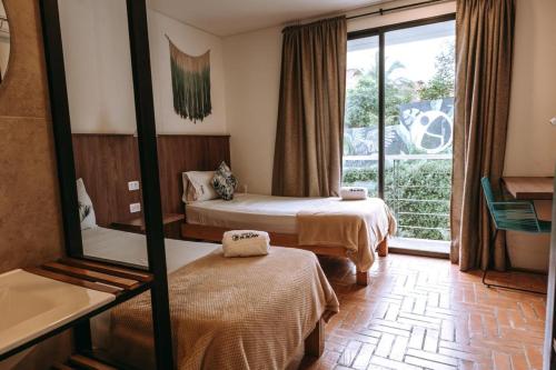 a room with two beds and a tub and a window at Hotel Macaw Cúcuta in Cúcuta
