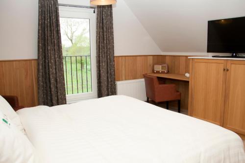 a bedroom with a bed and a desk and a window at Vakantiehuis 1 - Ter Douve in Heuvelland