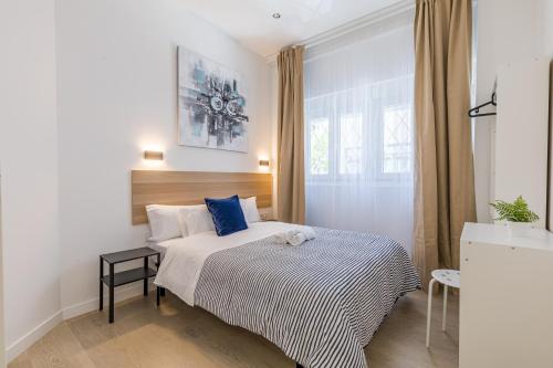 a small bedroom with a bed with blue pillows at LooP Alcala in Madrid