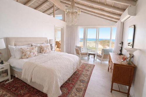 a bedroom with a bed and a room with a view of the ocean at Ashore - Beachfront Paradise in St. Helena Bay