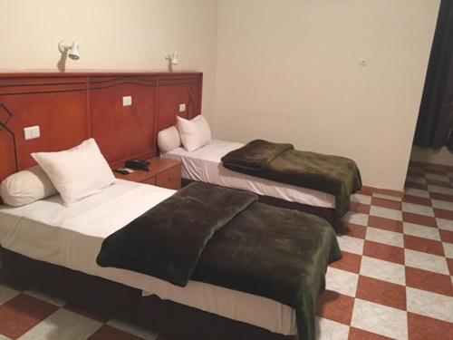 Habitación de hotel con 2 camas y suelo a cuadros en Hotel Emira, en Nouakchott