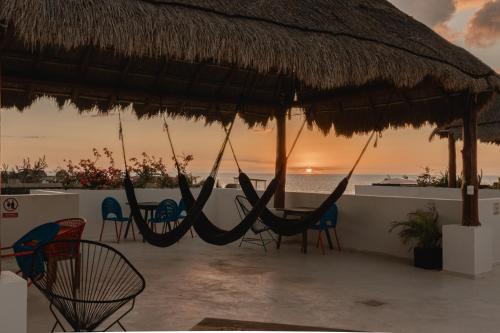 a beach with chairs and hammocks and a sunset at Casa Astral Hotel Boutique and Apartments in Holbox Island