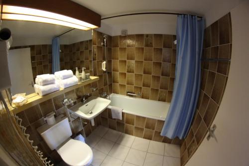 a bathroom with a sink and a toilet and a tub at Hotel Surselva in Surcuolm