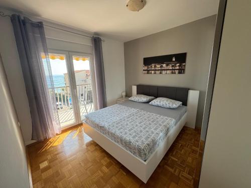a bedroom with a bed and a large window at Apartman Marta in Podstrana