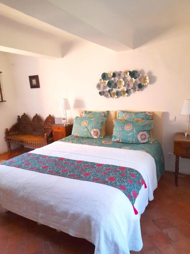 a bedroom with a large bed with blue and green pillows at La Cachette centre historique village in Roussillon