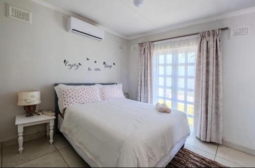 a white bedroom with a bed and a window at La Lucia Sleepover in Durban