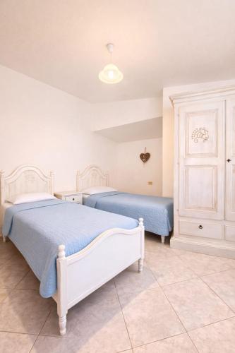 a bedroom with two beds with blue sheets at Le Arcada - Appartamenti diffusi nel cuore del centro storico di Orosei in Orosei