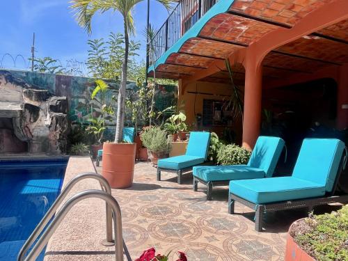 a patio with blue chairs next to a swimming pool at Le Colibri - 1 Min Beach - Pool - Serenity in La Peñita de Jaltemba