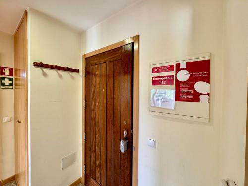 a hallway with a wooden door and a sign on a wall at Maria Borges Alojamento Local in Póvoa de Varzim