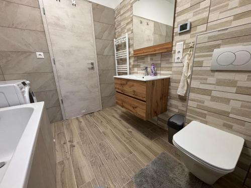 a bathroom with a toilet and a sink and a tub at KutyaGazdi Apartman in Balatonfenyves