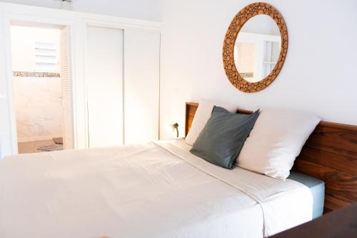 a bedroom with a white bed with a mirror on the wall at Quiet loft studio - Pinel side in Cul de Sac