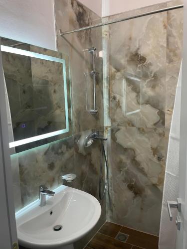 a bathroom with a sink and a shower with a mirror at Clean City Agrotourism in Durrës